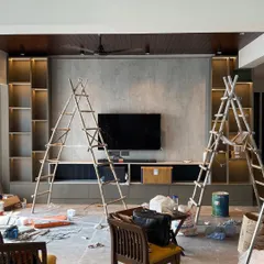 The 'before' phase of a living room project in Lotus 300, Noida. This image shows the space during construction, with ladders and materials, as our team works on the custom-built TV unit and shelving.