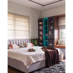 A wider view of the bedroom, showing the balance between comfort and style. The room includes a cozy window seat for reading and a custom bookshelf with a pop of teal for a touch of personality.