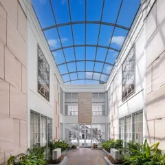 Another view of the glass-roofed courtyard in The Grand Alabaster, showcasing how it transforms the central corridor into a sun-drenched gallery. Lined with lush plants, it feels as though the sky is part of the home, blurring the line between inside and out.