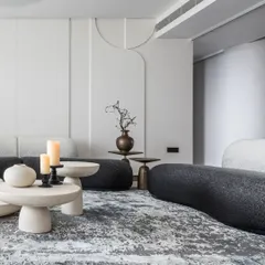 I love to play with form and flow. This living room uses bold, curvy furniture in a sleek black-and-white palette to create a dynamic yet inviting social hub. The sculptural silhouettes and circular stone tables create a rhythm that is modern and full of personality.