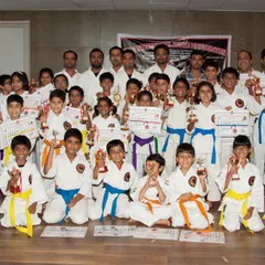A group of proud students after a successful belt grading ceremony. They are holding their new certificates and trophies, marking a new chapter in their karate journey.