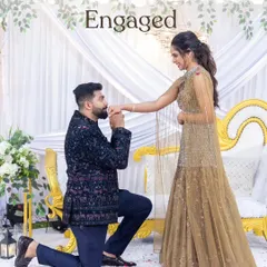 The moment it becomes official. The groom gets down on one knee to propose during their engagement ceremony, set against a beautiful backdrop of white drapes and florals. A classic, romantic gesture to start their journey.