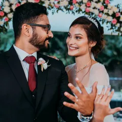 A happy portrait of a newly engaged or married couple, smiling at each other as they proudly show off their rings.