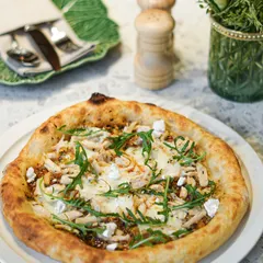 Our roasted chicken and pesto pizza, topped with fresh rocket and goat cheese. This gourmet pizza combines savory chicken with the bright flavors of our signature pesto.