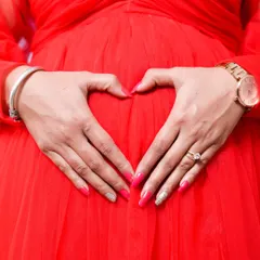 A close up shot focusing on the heart of the matter. Making a heart shape with your hands on your belly is a classic and sweet pose that symbolizes all the love you have for your baby.