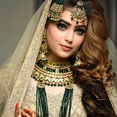 A breathtaking close-up of a bride in her gorgeous gold and green ensemble. This portrait highlights the flawless makeup, intricate jewelry, and the serene expression of the bride on her special day.