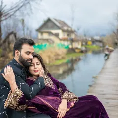 A tender moment captured on a wooden pier by Dal Lake. The bride rests in the groom's arms, with the unique houseboats and calm waters of Kashmir creating a picturesque and romantic setting.