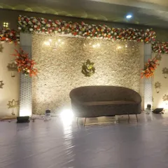 A closer view of the stage, focusing on the texture of the dense white floral backdrop and the simple, curved sofa for the couple.
