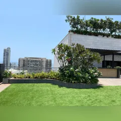 Even on a rooftop, we can create the feeling of a real garden. This design features a rolling lawn bordered by curved planters filled with flowering shrubs and trees, softening the hard edges of the urban environment.