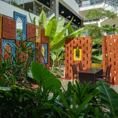 A vibrant courtyard at SAP Labs, inspired by traditional Rajasthani architecture. The design uses colorful walls, brick jali screens, and lush tropical planting to create a unique and culturally rich breakout space for employees.