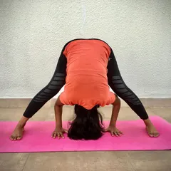 A student demonstrates Prasaritha Padottanasana, a wide-legged forward bend. This inversion increases blood flow to the head and strengthens the upper body.