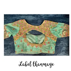 This pastel green blouse features a keyhole back and is covered in colorful floral threadwork embroidery.