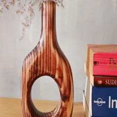 This hand-carved wooden vase, with its unique cutout design and rich wood grain, is a piece of art in itself. It's perfect for holding dried flowers or standing alone as a sculpture.