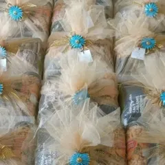 This is the final look of my in-room wedding hampers, filled with snacks and treats. Each one is beautifully wrapped in sheer netting with a bright blue floral accent, ready to be placed in guest rooms.
