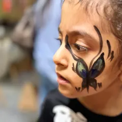A delicate butterfly design painted on a child's cheek. Our face painters can create all sorts of designs, from spooky Halloween looks to beautiful and whimsical art.