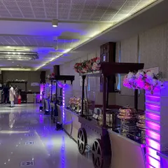 A stylish buffet setup at Samriddhi Banquets, featuring our unique cart-style counters. The purple ambient lighting and floral arrangements create a modern and elegant dining atmosphere.