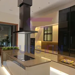 This is the centerpiece of our Bharatpur island kitchen project. The sleek island features an integrated hob and provides ample counter space, while the suspended chimney adds a modern, sculptural element. We used a combination of high-gloss laminates and warm wood tones, complemented by strategic under-cabinet and kick-plate lighting to create a luxurious and inviting atmosphere.