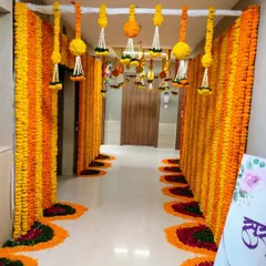 We transformed this building corridor for the groom's welcome. The passageway is lined with walls of orange and yellow marigolds, with floral rangoli on the floor and hanging tassels from the ceiling, creating a complete festive experience.