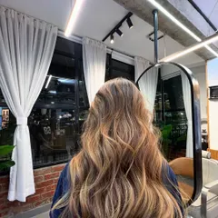 A back view of a lived-in brunette style. The placement of colour is designed to contour and add dimension, making the hair appear fuller and more vibrant.