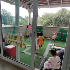 A view from the classroom into the "Home & Community" play area on our terrace. This setup seamlessly blends indoor and outdoor learning, giving children space to explore.