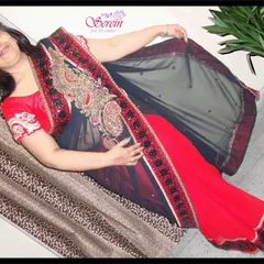 A happy client looking elegant in a custom Serein partywear saree. This red and black net saree is adorned with heavy paisley embroidery along the border, making it a stunning choice for any formal occasion.