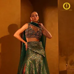Wrapped in the richness of brocade. This emerald green lehenga features a modern slit skirt and a heavily embellished blouse, perfect for a grand entrance.