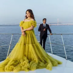 A stylish pose on the bow of a boat, featuring the tiered lime green ball gown. This image perfectly captures a modern and glamorous pre-wedding or maternity shoot.