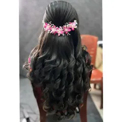 A classic half-updo with big, bouncy curls. I added a beautiful pink floral hairpiece to match the bride's reception saree, creating a cohesive and elegant look.
