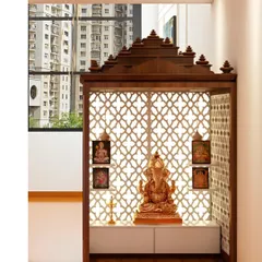 This pooja mandir, set against a window with a city view, is a perfect urban sanctuary. The traditional wooden structure with intricate jali work and a spacious cabinet below is both beautiful and functional.
