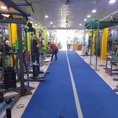 A full view of our training floor. You can see the long turf track for sprints and sled work, with various strength stations and free weight areas alongside it. There is space for everyone to focus on their workout.