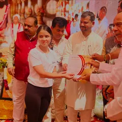 A student receiving her certificate and award at a yoga event, her smile says it all.