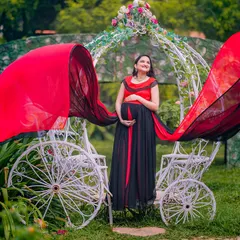 A truly royal portrait for a mom-to-be. The red and black flowing gown creates a dramatic effect as it catches the wind, set against the whimsical white carriage prop for a perfect fairy tale maternity shoot.