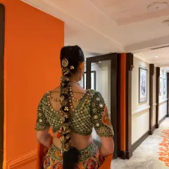 The bride walking down a hallway, showing how a long, traditional braid moves and complements the entire bridal ensemble. The hairstyle is both a statement piece and a functional part of the look.