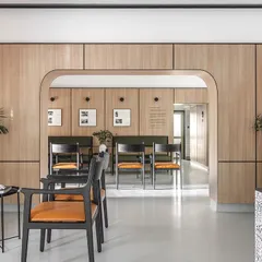 A wide view of the reception and main waiting hall. The arched entryway softens the linear geometry of the space, guiding patients from the welcoming area into the tranquil waiting zones.