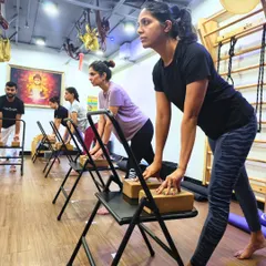 A glimpse into one of our Foundation Workshops. Here, students use chairs and blocks to learn proper alignment in a standing pose. This group setting fosters focus and shared energy, with instructors providing guidance to ensure everyone finds stability and strength.