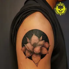 A dotwork style lotus flower against a solid black circle. This technique, called stippling, uses tiny dots to create shading and texture, giving the tattoo a unique look.