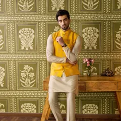 Brighten up the Haldi ceremony with this vibrant yellow waistcoat. I've detailed it with subtle hand-embroidery and paired it with a simple beige kurta pyjama, creating a look that is festive, comfortable, and effortlessly stylish.
