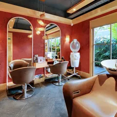 Even the more private rooms at Enrich Salon, like this hair wash area, feature large windows with views of the garden. The rich red walls create a warm, intimate contrast to the vibrant green outside.