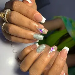 Learn classic French manicures with a modern twist. This example combines the traditional white tip with accent nails featuring silver glitter and iridescent crystal embellishments, a popular choice for bridal parties.