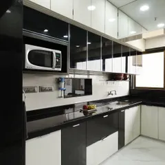 This U-shaped kitchen features a classic black and white color scheme with high-gloss cabinets and a black granite countertop. The layout provides ample counter space and includes a dedicated niche for the microwave.