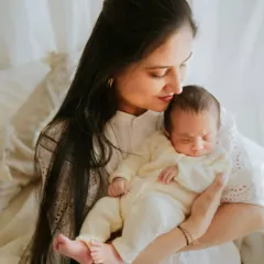 A mother holds her sleeping newborn close. The soft, natural window light and their peaceful expressions make this a truly serene and beautiful portrait.
