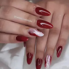 When in doubt, keep it classy. This beautiful set features long, almond-shaped nails in a classic deep red, with two accent nails that have a white and red marble design.