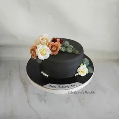 You can never go wrong with a classic black cake and flowers. This design is simple yet striking, with a spray of delicate flowers providing a beautiful contrast against the dark, smooth finish.