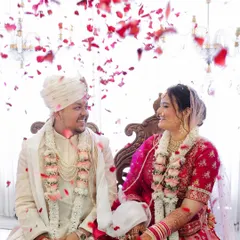 A shower of rose petals rains down on the happy couple. This joyful moment from their wedding ceremony is full of color, emotion, and celebration.