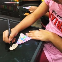 Getting ready for Easter with some bunny craft. Here, a young artist is carefully drawing a face on her bunny, which is made from a simple wooden spoon and paper.