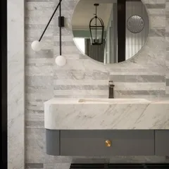A full view of the Parisian-inspired bathroom. The vanity is set against a backdrop of horizontally stacked marble tiles, with a modern, minimalist light fixture adding a contemporary touch to the classic materials.