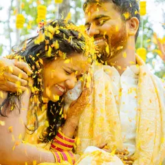 Pure, unadulterated joy. A candid shot of a couple laughing as they are covered in turmeric and flower petals during their Haldi in Jim Corbett.