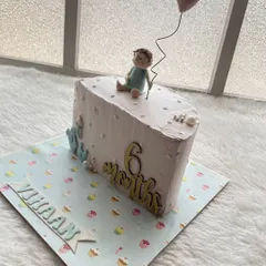 A simple and sweet half-cake for a 6-month-old, featuring a little baby topper holding a heart balloon.