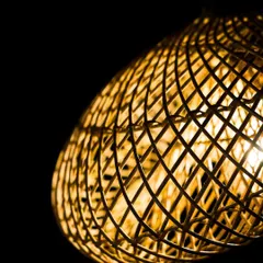 A close-up of the sculptural lamp's intricate weave. The complex, crisscrossing lines of rattan demonstrate a mastery of the craft and create a visually stunning texture.