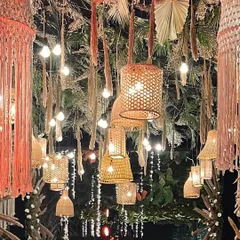 Another angle of the stunning ceiling installation, showing the interplay of textures between the macrame, woven lamps, and dried florals, all lit by warm Edison bulbs.